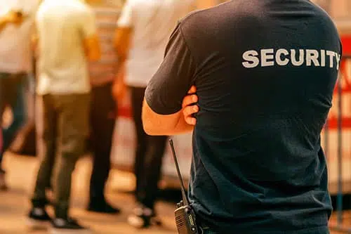 "A person stands in orange sportswear with a bent elbow and gestural hand movement. The picture shows a detail of the sleeve and leg at an event."